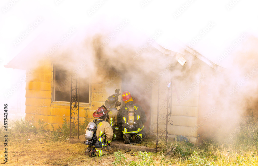Fototapeta premium Firemen battle a house blaze that has consumed the entire building'