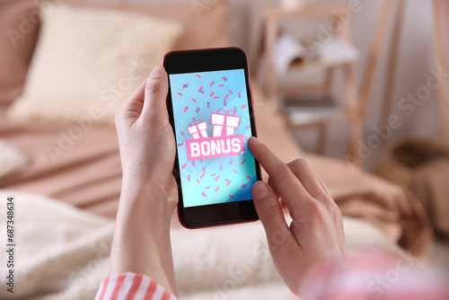 Bonus gaining. Woman using smartphone indoors, closeup. Illustration of gift boxes, word and falling confetti on device screen photo