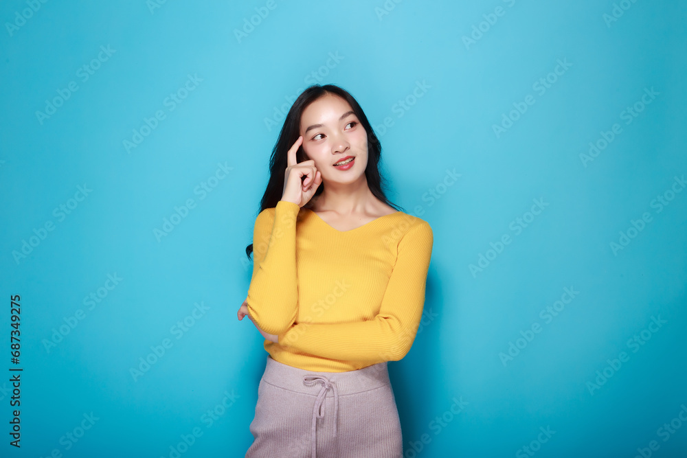 Portrait of a beautiful young woman in a light blue background, happy and smile, posting in stand position, Pretty girl makes a thoughtful expression. Portrait of a beautiful young woman in a light blue background, happy and smile, posting in stand position, Pretty girl makes a thoughtful expression.