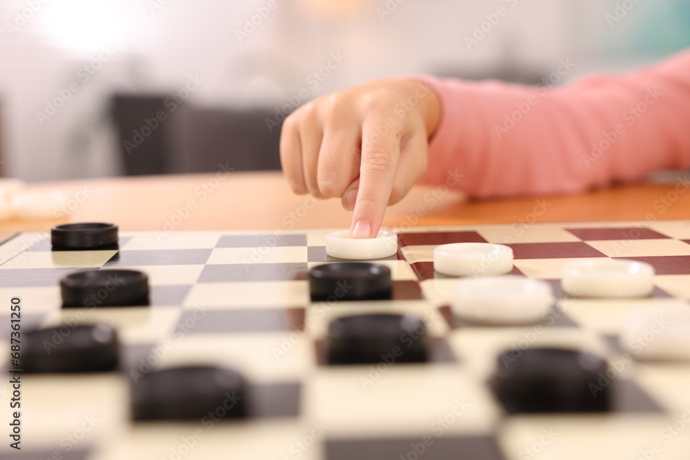 Girl playing checkers at table indoors, closeup Girl playing checkers at table indoors, closeup
