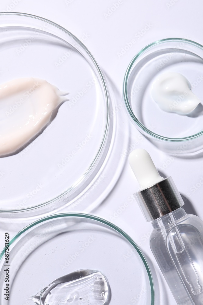 Petri dishes with samples of cosmetic serums and bottle on white background, flat lay Petri dishes with samples of cosmetic serums and bottle on white background, flat lay
