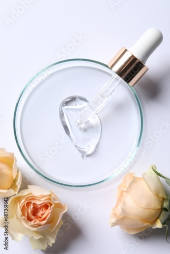Petri dish with sample of cosmetic serum, pipette and rose flowers on white background, flat lay