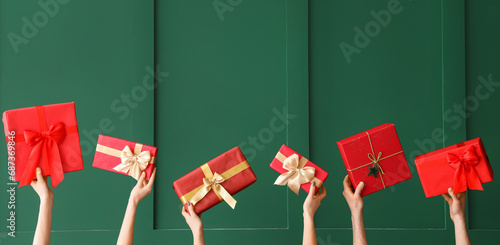 Many hands with Christmas gifts on green background