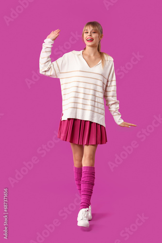 Young woman dressed as doll on purple background