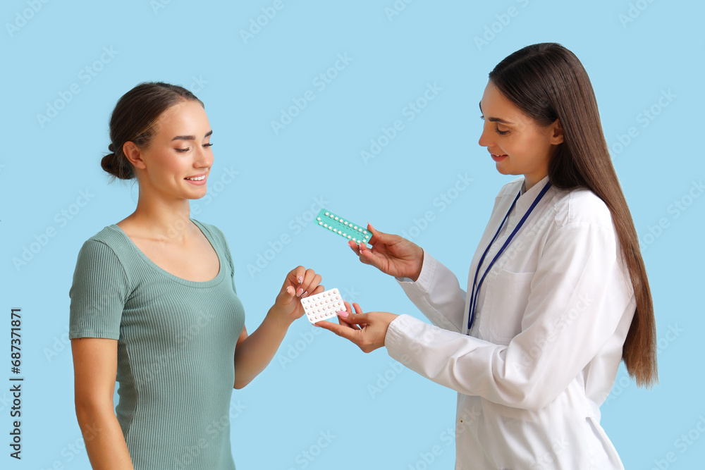 Female gynecologist giving contraceptive pills to patient on blue background Female gynecologist giving contraceptive pills to patient on blue background
