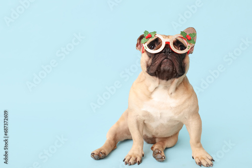 Cute pug dog in Christmas glasses on blue background © Pixel-Shot