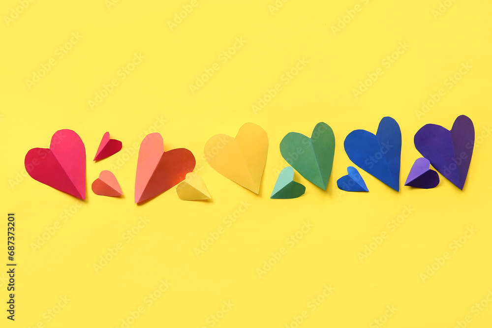Colorful paper hearts on yellow background. LGBT concept