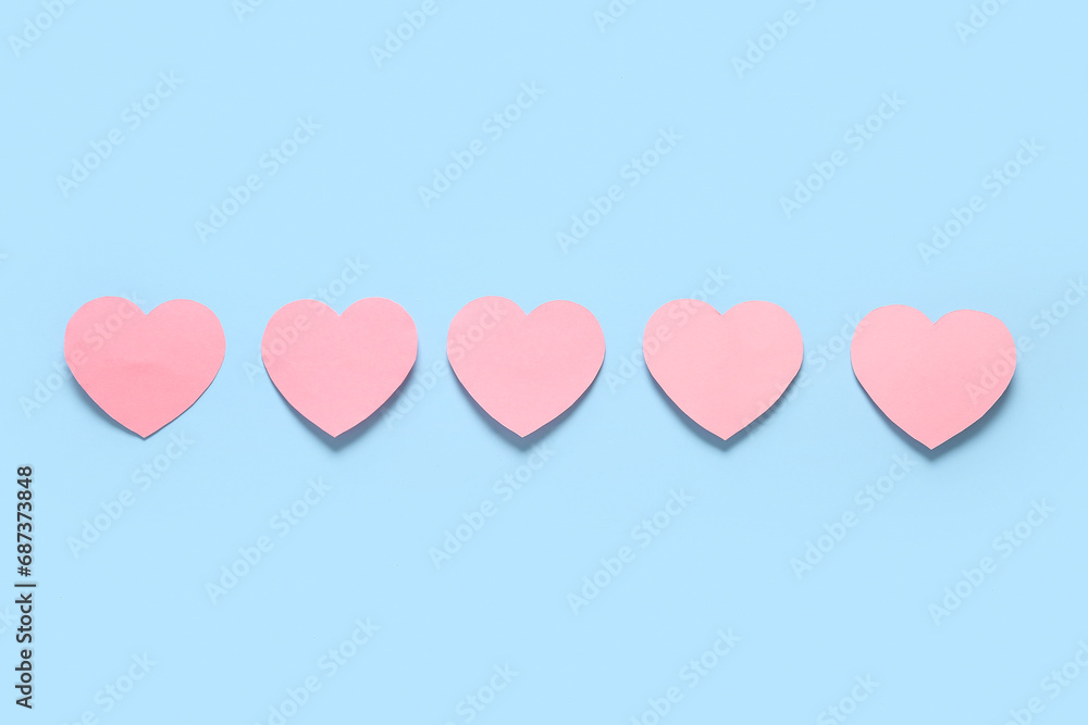 Row of pink paper hearts on color background. Valentines Day celebration