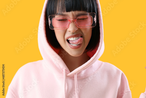 Beautiful young stylish woman in sunglasses on yellow background photo