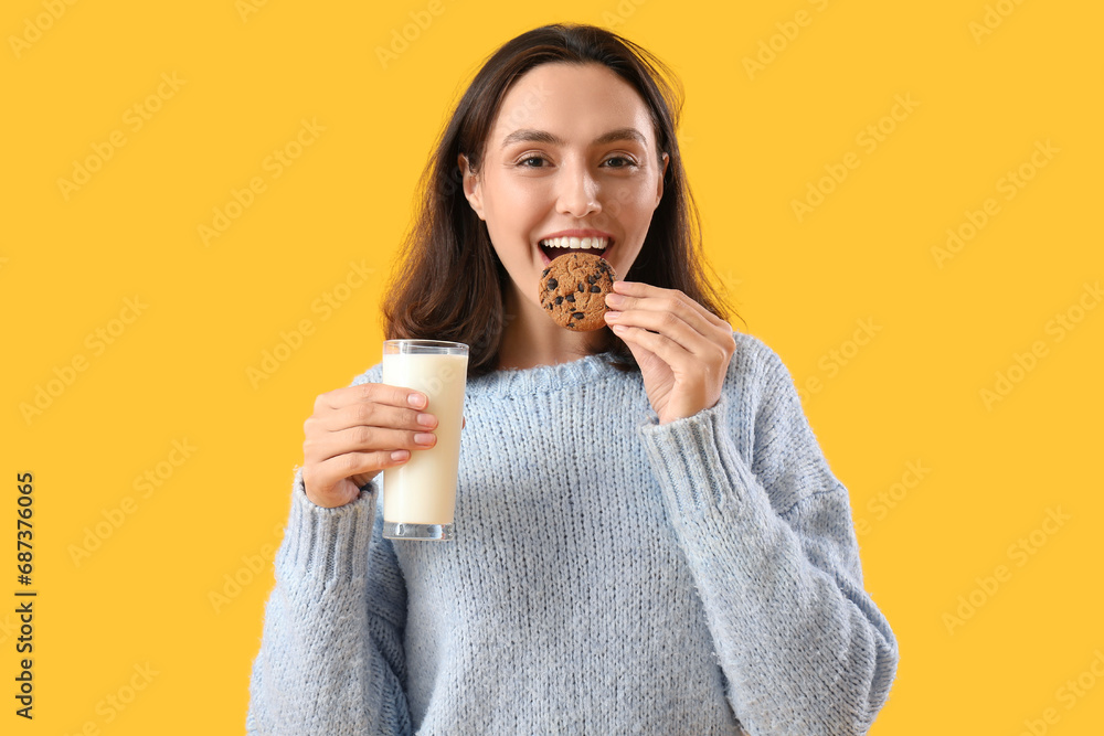 Beautiful young woman with tasty cookie and glass of milk on yellow background Beautiful young woman with tasty cookie and glass of milk on yellow background