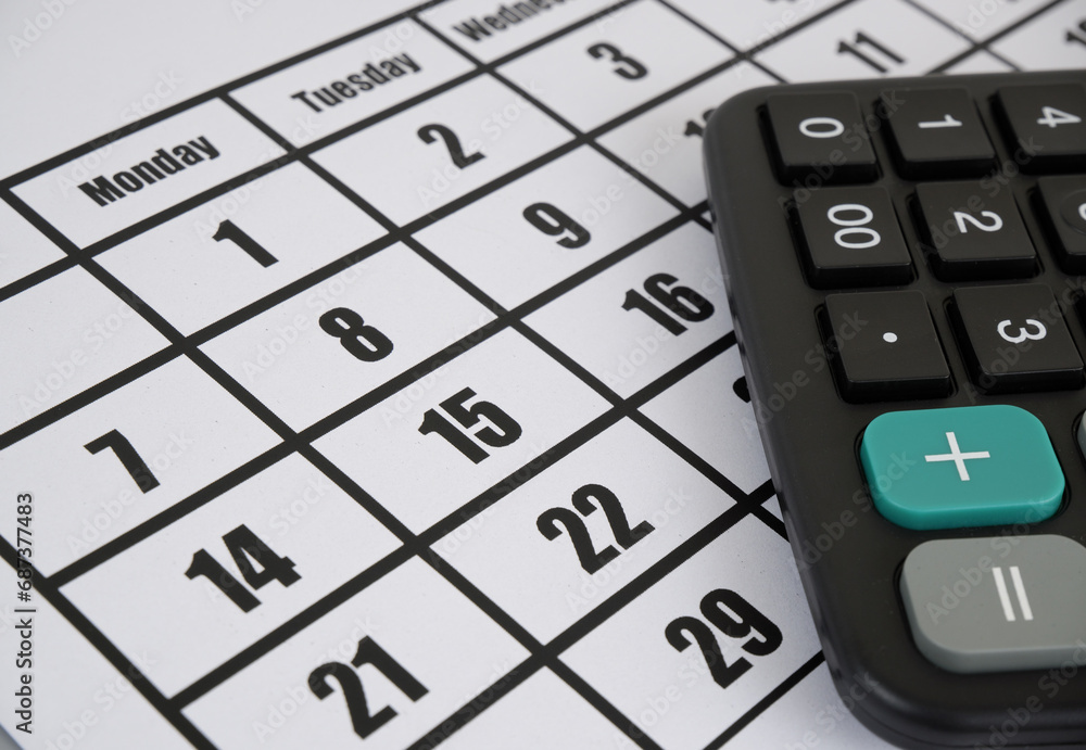 Close-up of black calculator on calendar page Close-up of black calculator on calendar page