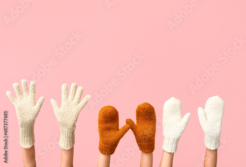 Hands in warm gloves and mittens on pink background photo