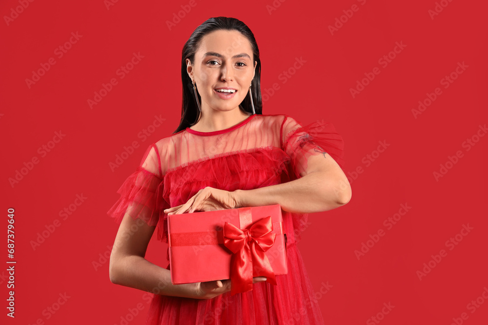 Beautiful woman with Christmas present on red background Beautiful woman with Christmas present on red background