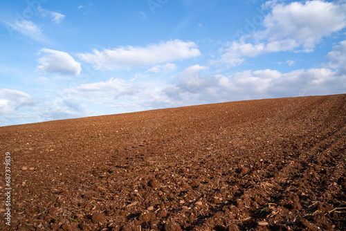 Plowed farm field with brown soil and a blue sunny sky