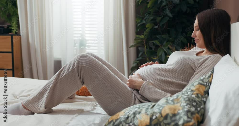 Beauty of motherhood as a woman in stylish pajamas tenderly touches her belly, radiating with love and anticipation. Beauty of motherhood as a woman in stylish pajamas tenderly touches her belly, radiating with love and anticipation.