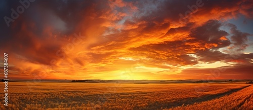 Autumnal sunset in prairies - vibrant sunset with orange sun, dark cloudy sky, and harvested fields. © AkuAku