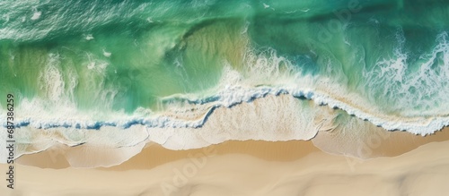 Aerial view of green waves and a sandy beach.