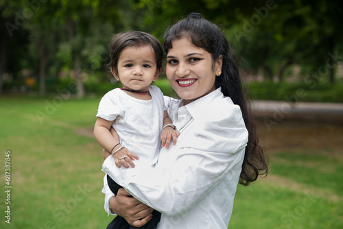 Beautiful Young indian mom enjoying with her daughter in the park or garden. © gajendra