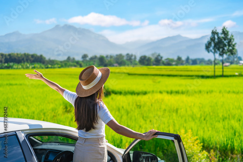 Young woman travelers with car watching a beautiful rice paddy fields and mountain view while travel driving road trip on vacation, Travel concept