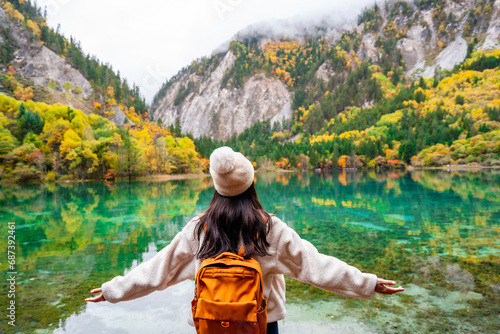 Young female tourist looking at beautiful autumn scenery landscape at jiuzhaigou national park in Sichuan, China photo