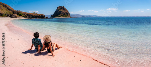Young couple tourism enjoying the tropical pink sandy beach with clear turquoise water at Komodo islands in Indonesia
