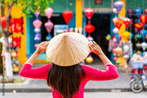 Young female tourist in Vietnamese traditional dress looking at a souvenir shop in Hoi An Ancient town photo
