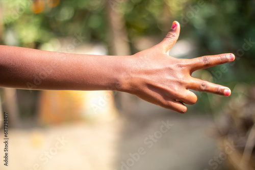 A man points his two fingers forward and the thumb of his hand pointing up and blurred background © Rokonuzzamnan