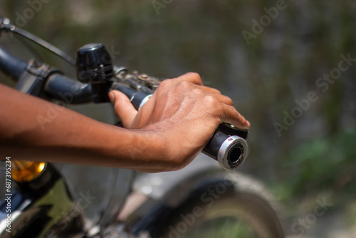 A man is holding a bicycle handle with his hands and a blurred background