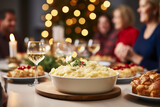 Mashed potatoes served on festive table with family in background at home