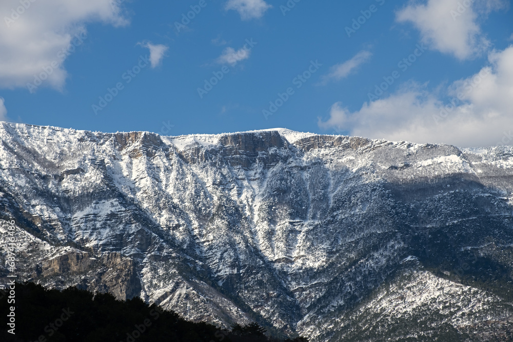 Snow-capped mountains blue sky background. Winter landscape with trees and rocks on the background of a beautiful sky with clouds. Space for text. Atmospheric background for website design, notebook