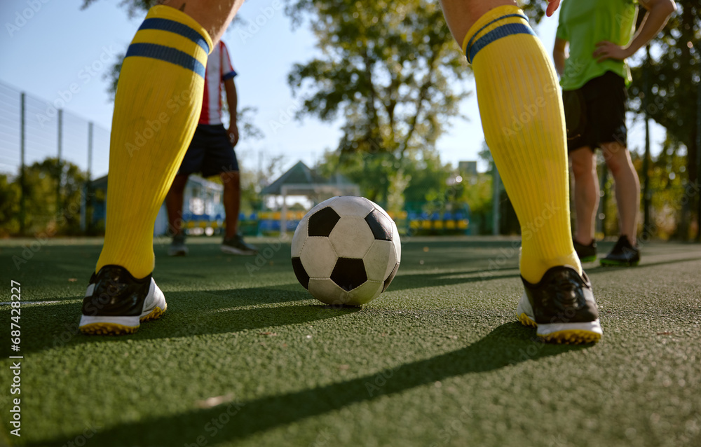 Fototapeta premium Closeup soccer ball and sportsman legs over grass football field