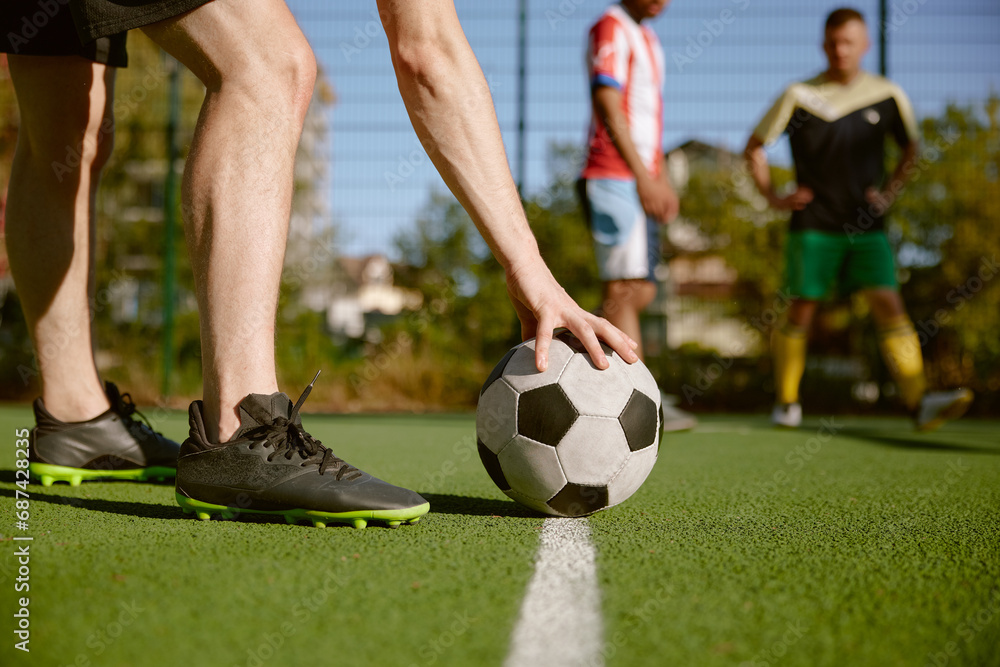 Obraz premium Sportsman putting soccer ball on white line to start game