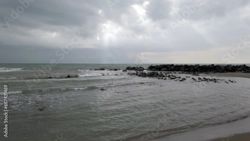 Seascape at rough sea and dramatic sky with sunbeam between gray clouds threatening bad weather