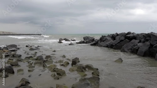 Scenic bad weather on rocky bay with rough sea and dramatic sky breakwaters stop sea waves agitated by wind