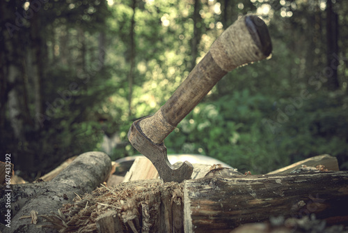 A lumberjack's axe is stuck in a log. To cut wood for firewood. An axe with a wooden handle. photo