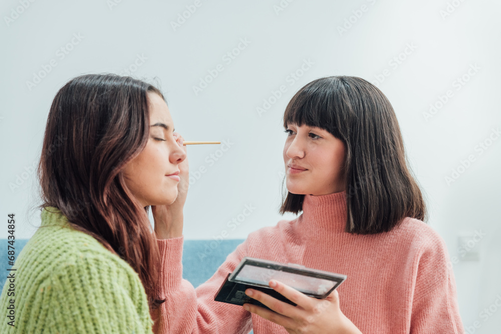 Young ethnic visagiste applying eyeshadow on Hispanic girlfriend Young ethnic visagiste applying eyeshadow on Hispanic girlfriend