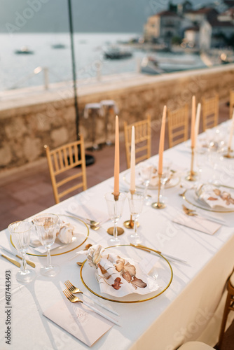 Knotted napkins lie on plates on a holiday table next to invitations © Nadtochiy