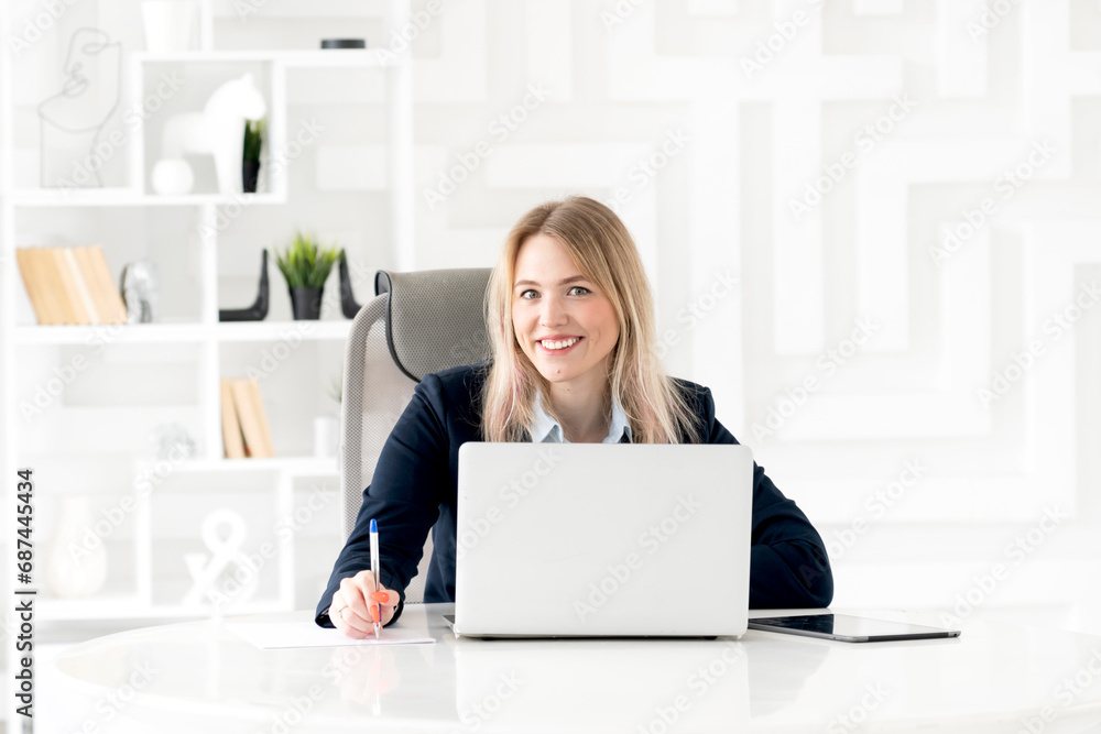 Portrait of successful and attractive business woman working on laptop ...