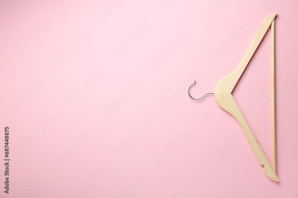 Wooden hanger on pink background, top view