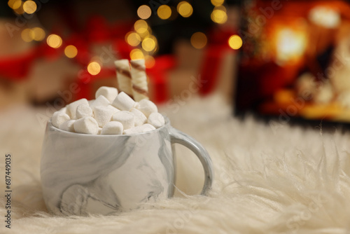 Christmas cocoa with marshmallows and wafer sticks in cup on soft carpet indoors, closeup. Space for text