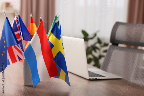Different flags and laptop on wooden table indoors, selective focus