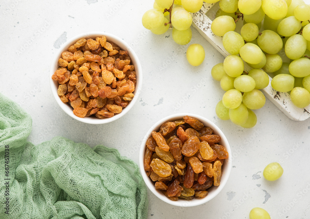 Fototapeta premium Sweet dried green raisins with ripe raw grapes on light background.Top view.