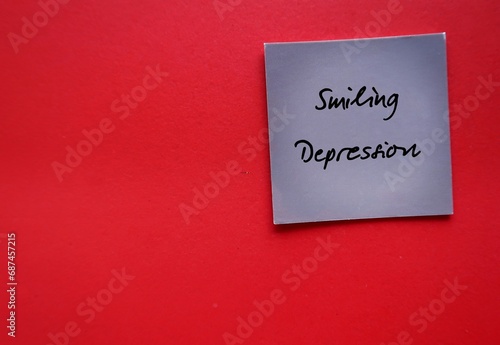 Card on copy space red background with text Smiling Depression - refers to form of depression in which person appears to be happy thriving on outside, while suffering inside