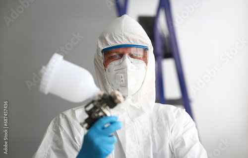 Workman hold in arm airbrush gun wearing protective suit portrait