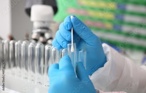 Forensic scientist conducting criminal investigation aganist laboratory background. Holds cotton swab with sample of dna and a test tube in his hand. Tets paternity concept. photo