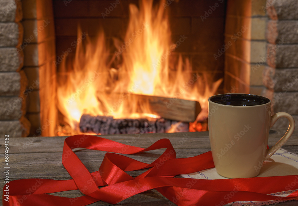 In front of a cozy fireplace, in a country house, during winter holidays, a mug of coffee and a festive red ribbon In front of a cozy fireplace, in a country house, during winter holidays, a mug of coffee and a festive red ribbon