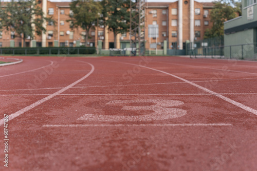 Lane number 3 of the athletics track. Image of the reddish rubber of the high performance sports track of a local city.