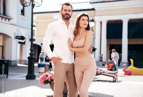 Beautiful fashion woman and her handsome elegant boyfriend in white shirt. Sexy brunette model in summer clothes. Fashionable confident couple posing in street Europe. Brutal man and female outdoors