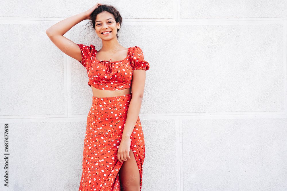 Young beautiful smiling hipster woman in trendy summer red dress. Carefree woman posing in the street near wall. Positive model outdoors in at sunny day. Cheerful and happy Young beautiful smiling hipster woman in trendy summer red dress. Carefree woman posing in the street near wall. Positive model outdoors in at sunny day. Cheerful and happy