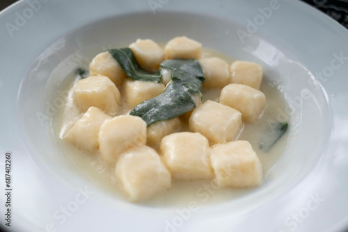 Gnocchi in sauce of sage butter, served in a deep plate, decorated with a sage leaf